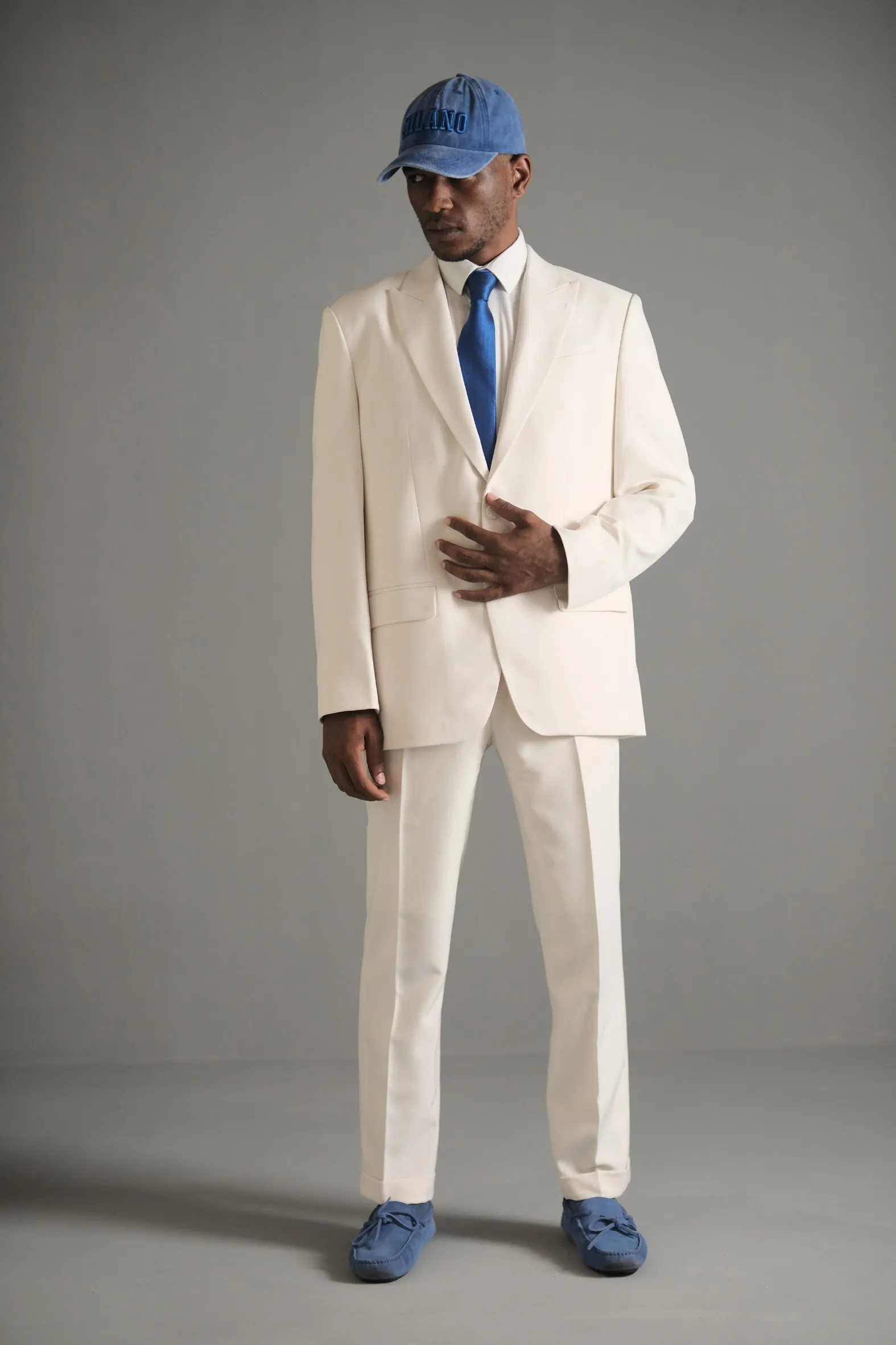 Travon Ridley-Evans in the ivory suit from Sabi Sabi, with a blue cap and tie